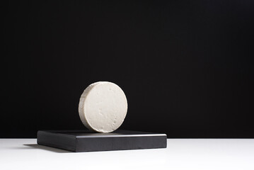 Queso cremoso de cabra sobre piedra negra y fondo negro. Concepto minimalista	
