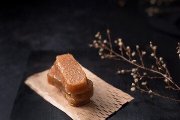 Dulce pasta de gelatina de membrillo dorado sobre una placa de madera negra