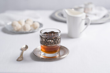 Un vaso de té clásico con dulces chocolates blancos cubiertos de coco en el cuadro blanco	