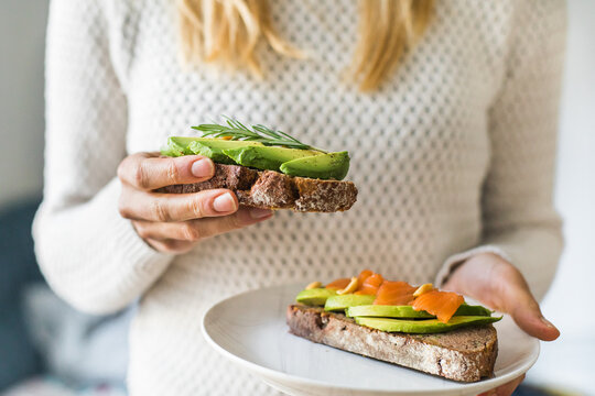 Close up of woman holding plate with avocado toast as fresh snack, day light. 