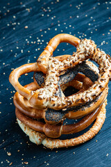 Fresh prepared homemade soft pretzels. Different types of baked bagels with seeds on a black background.