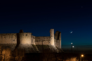 Fototapeta premium night falls over the castle of chinchón, the moon and neptune guard it. medieval castle with the moon at its side