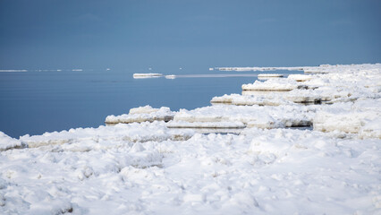 white pieces of ice floating in the sea, winter landscape from the sea, calm water, sky reflections in the sea
