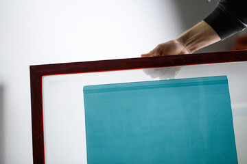 Craftsman holding screen with light sensitive emulsion for serigraphy