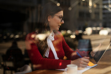 Beautiful young woman using digital tablet in cafe. Happy smiling woman enjoy in fresh coffee..