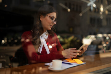 Beautiful young woman using digital tablet in cafe. Happy smiling woman enjoy in fresh coffee..