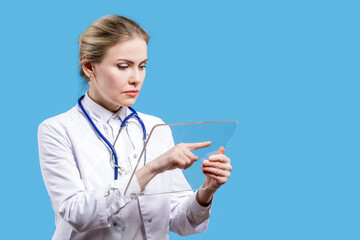A female doctor looks into a tablet on a blue background. Hospital. Chief Physician. Analyzes from...