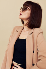 Obraz premium portrait of a woman in a beige jacket elegant style sunglasses light background