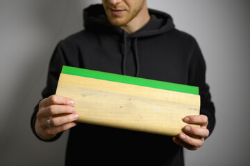 Cropped shot of artisan holding wooden and rubber squeegee isolated on grey 