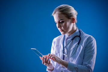 Analyzes from the laboratory. Therapist. Hospital. Chief Physician. A female doctor looks into a smartphone on a blue background