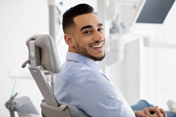 Dental Clinic Patient. Portrait Of Smiling Arab Male Posing In Dentist Chair