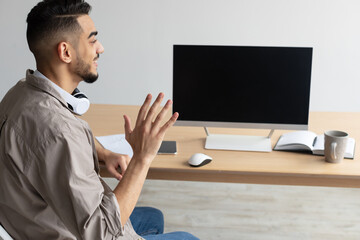 Arab man waving hand at blank empty computer monitor