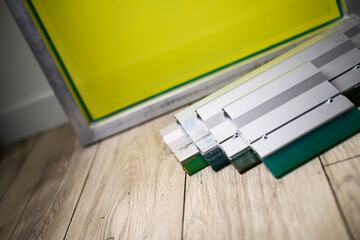 Close up view of squeegees on floor near frame for screen printing 