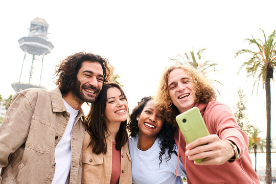 Happy smiling friends from diverse cultures and races taking selfie with smartphone outdoors. Cheerful people having fun