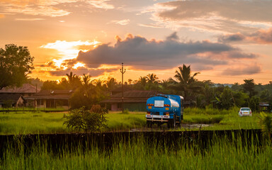 Fuel tanker standing on soil made village road with beautiful sunset scene in Indian village