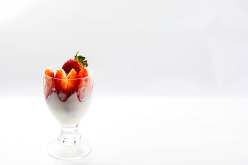 glass cup with strawberries and cream on white background