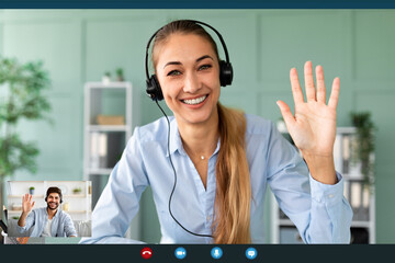 Happy female teacher wearing headphones while having video conference, waving and smiling to...