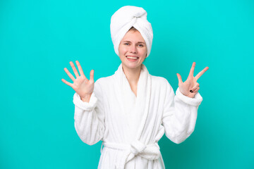 Young woman in a bathrobe isolated on blue background counting eight with fingers