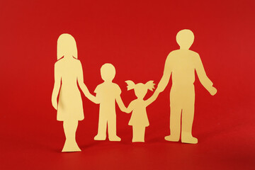 Paper family figure on red background. Child adoption concept