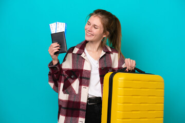 Young English woman isolated on blue background in vacation with suitcase and passport