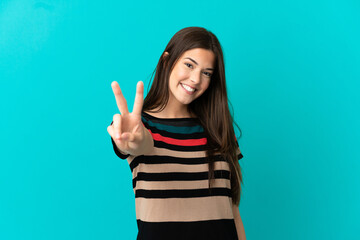 Teenager Brazilian girl over isolated blue background smiling and showing victory sign