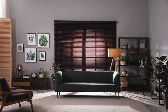 Stylish living room interior with comfortable sofa and green houseplants