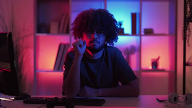Counting gesture. Hipster man. Meme expression. Confident guy showing one two three fingers sitting desk dark neon light room interior looped.