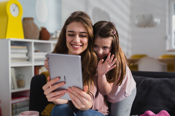 mother and daughter using digital tablet at home