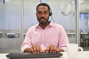Business Mann mit Headset schreibt auf PC Tastatur
