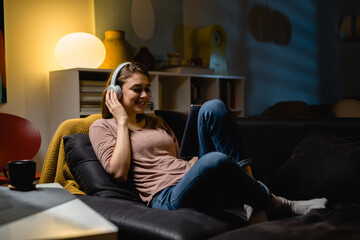 Obraz premium woman relaxing at home using digital tablet and listening music