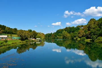 Fototapeta na wymiar Krka river near Novo Mesto in Dolenjska, Slovenia with a reflection of the sky and the trees in water