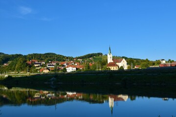 Fototapeta na wymiar View of the town of Krsko in Dolenjska, Slovenia with Sava river in front and forest covered hills behind and a reflection in the water