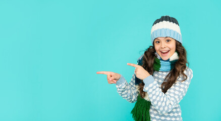 amazed kid with curly hair in hat and scarf. teen girl on blue background.