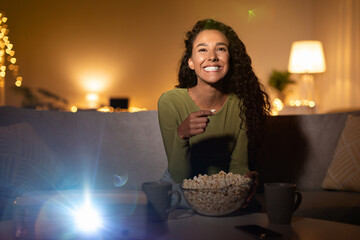 Woman Watching Film On Projector And Eating Popcorn At Home