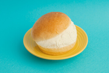 A Maritozzo Cake on A Yellow Plate on Blue Background, Italian Food or Sweet	