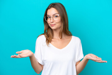 Fototapeta premium Young caucasian woman isolated on blue background With glasses and having doubts