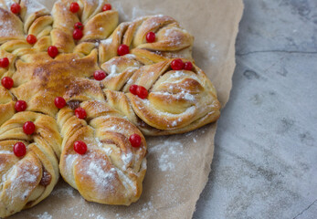 appetizing baked star cake with red berries and powdered sugar close-up on rough beige paper