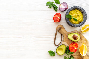 Homemade guacamole avocado dip in mortar with ingredients
