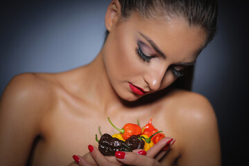 Beautiful girl holding a bunch of different colours hot pepper Carolina Reaper in her hands
