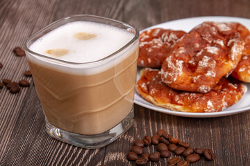 A cup of branded coffee in a scene of coffee beans and a wooden table top. Preparation of cappuccino.