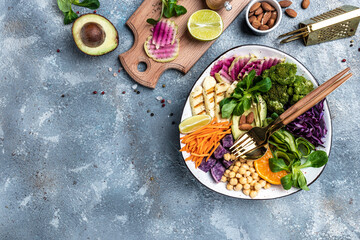 Obraz na płótnie Canvas Buddha bowl salad with halloumi cheese, avocado, cucumber, chickpeas, watermelon radish, potato purple sweet. ketogenic paleo diet. Clean eating, dieting, vegan food concept. top view