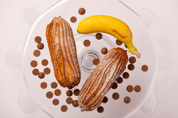 Eclairs with milk chocolate and banan served and deocarted on a tray