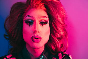 Drag queen looking at camera with neon color lights inside studio - Lgbtq concept