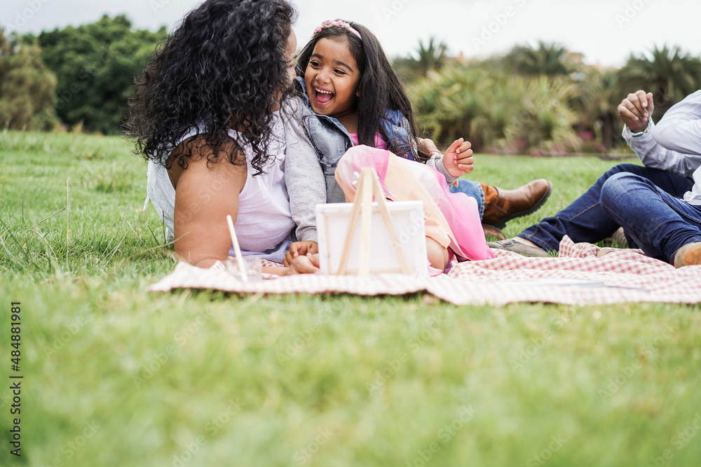 Poster Happy indian family having fun painting with children outdoor at city park - Mother day concept - Main focus on female kid face