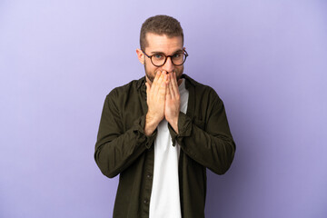 Young handsome caucasian man isolated on purple background happy and smiling covering mouth with hands