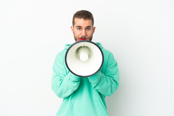 Young handsome caucasian man isolated on white background shouting through a megaphone to announce something
