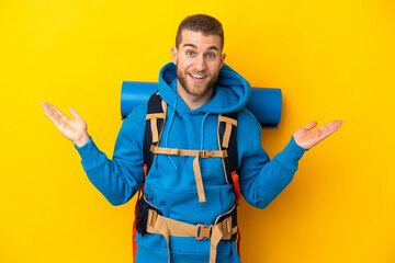 Young caucasian mountaineer man with a big backpack isolated on yellow background with shocked facial expression