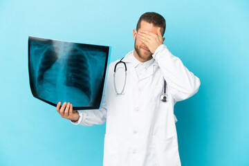 Professional traumatologist isolated on blue background covering eyes by hands. Do not want to see...