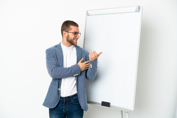 Young handsome caucasian man isolated on white background giving a presentation on white board and pointing to the side