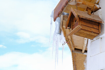 Bird's nest, birdhouse placed in the corner of the house, with a winter view, icicles hang from the roof.